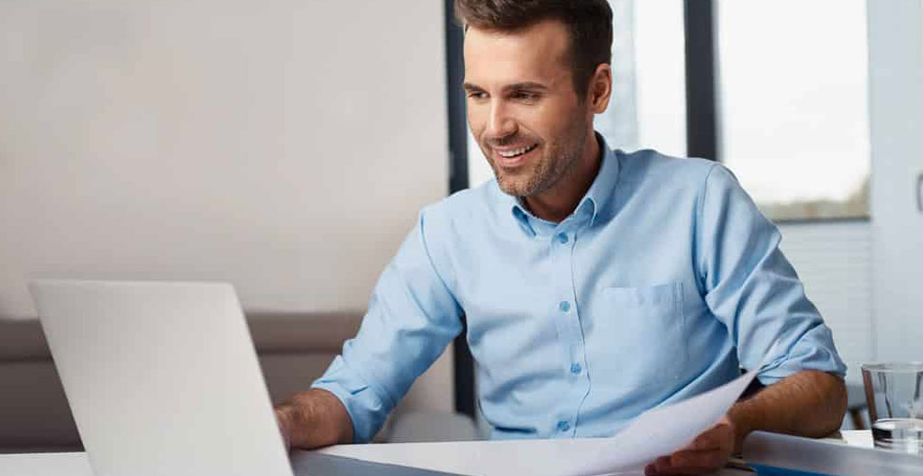 Femme consultant l'interface d'ouverture de Livret A en ligne sur ordinateur avec formulaire en français visible et smartphone à proximité sur bureau lumineux